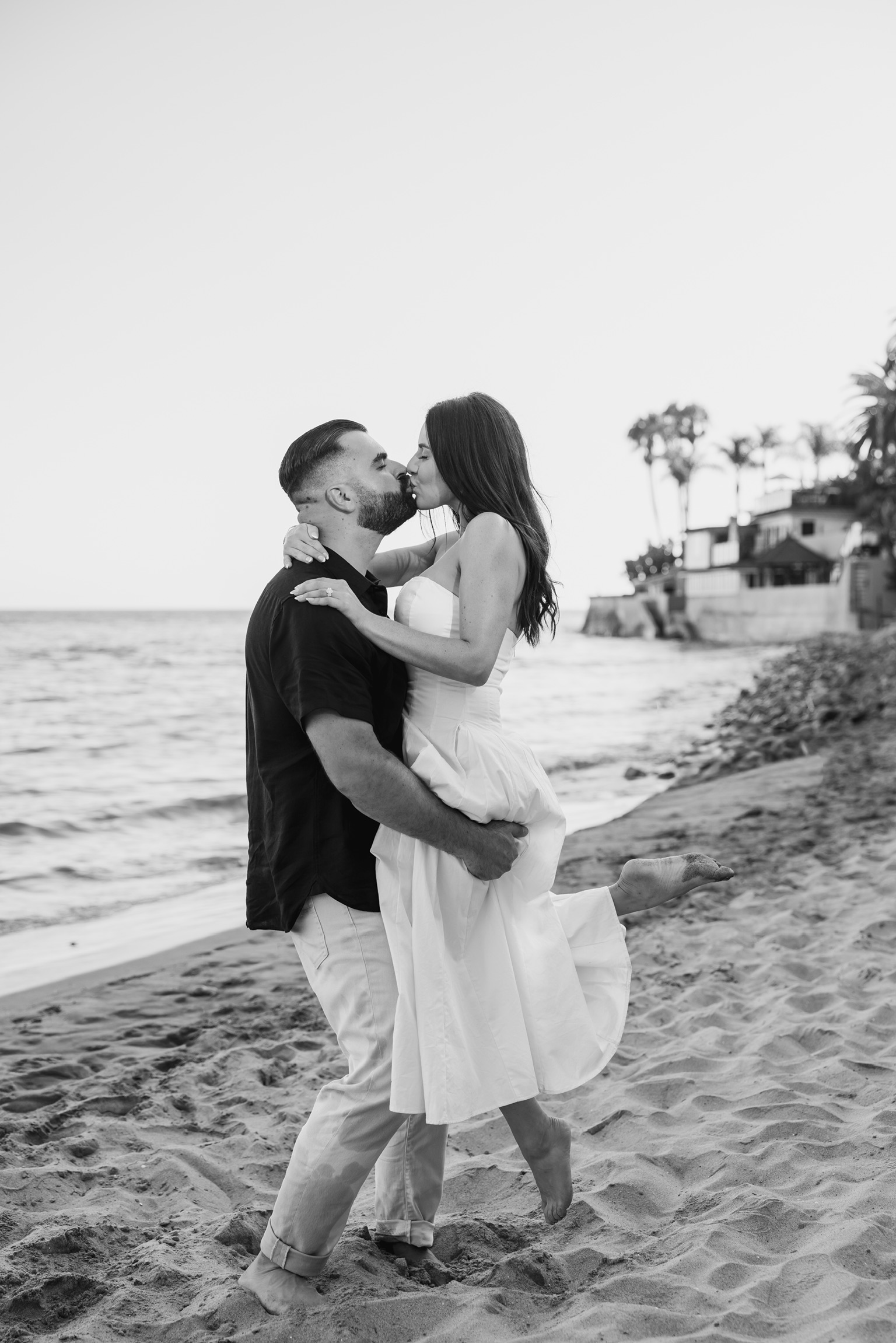 Nicholas lifting Belinda as they kiss on the beach